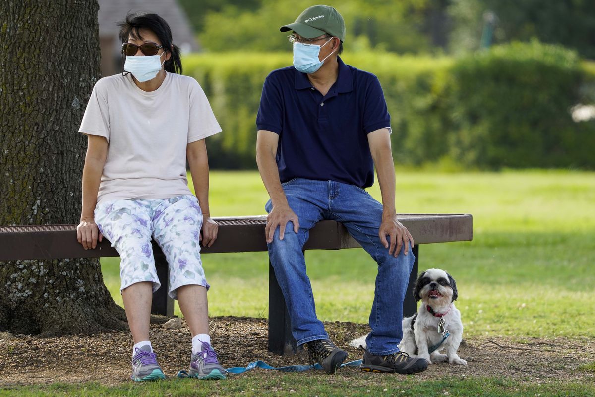 Jeff and Raynette Ho wear face masks as they sit with their dog at Custer Park on Thursday, July 2, 2020, in Richardson, Texas. Gov. Greg Abbott on Thursday ordered Texans in most of the state to wear face masks in public beginning Friday at noon as cases of the coronavirus surge. (Smiley N. Pool)