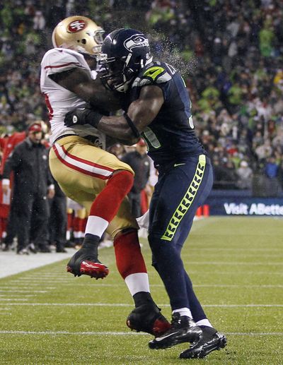 Seattle’s Kam Chancellor, right, in the final year of his contract, slams San Francisco’s Vernon Davis. (Associated Press)