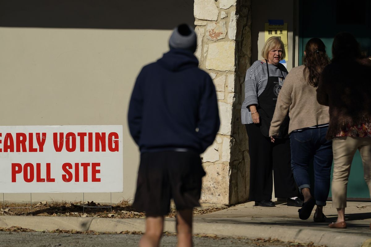 A poll worker meets voters at the entrance to an early voting site, Monday, Feb. 14, 2022, in San Antonio. Early voting in Texas began Monday. (Eric Gay)