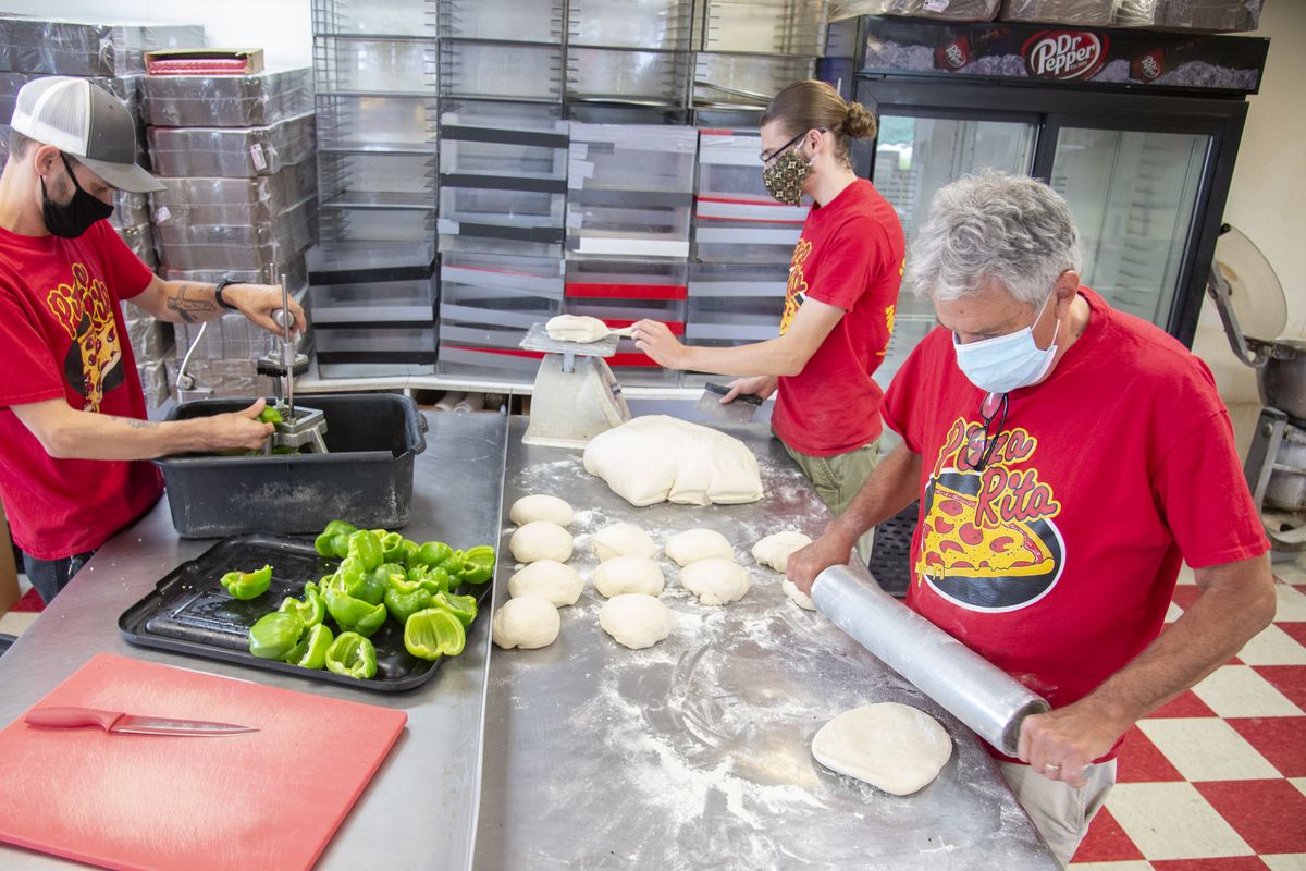 Pizza Rita owner Brian Dickman, right, and employees Greg Berdit, left, and Gabriel Meek, center, prepare dough and toppings for the day’s pizza’s Monday, Aug. 24, 2020 at the store at 502 W. Indiana in North Spokane. Pizza Rita will join other restaurants for the fair food drive-through event, which will take place in Spokane and Coeur d’Alene even though the Spokane Interstate Fair and the North Idaho Fair are cancelled due to COVID19.  (Jesse Tinsley/The Spokesman-Review)
