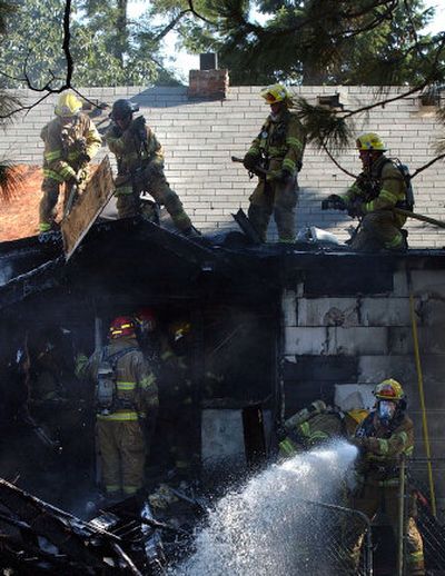 
Spokane firefighters take care of a house fire on Desmet Avenue on Sunday. 
 (Liz Kishimoto / The Spokesman-Review)