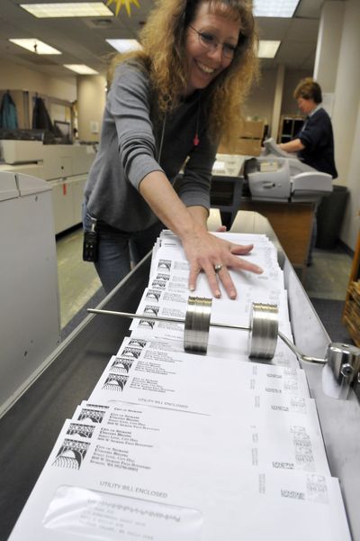 Bobbe Moxley, left, and Joyce Brede run machines that process Spokane utility bills and other mass mailings Monday in the city’s mail center. (Jesse Tinsley)