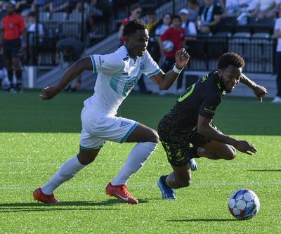 Spokane Velocity’s Andre Lewis, left, slides past Omaha’s Lagos Kunga before scoring a first-half goal against Union Omaha on May 11 at ONE Spokane Stadium.  (JESSE TINSLEY/THE SPOKESMAN-REVIEW)
