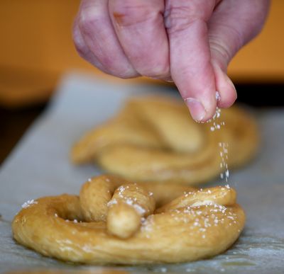 Brush homemade pretzels with egg wash, sprinkle with coarse salt and bake.  (Elizabeth Flores / TNS)