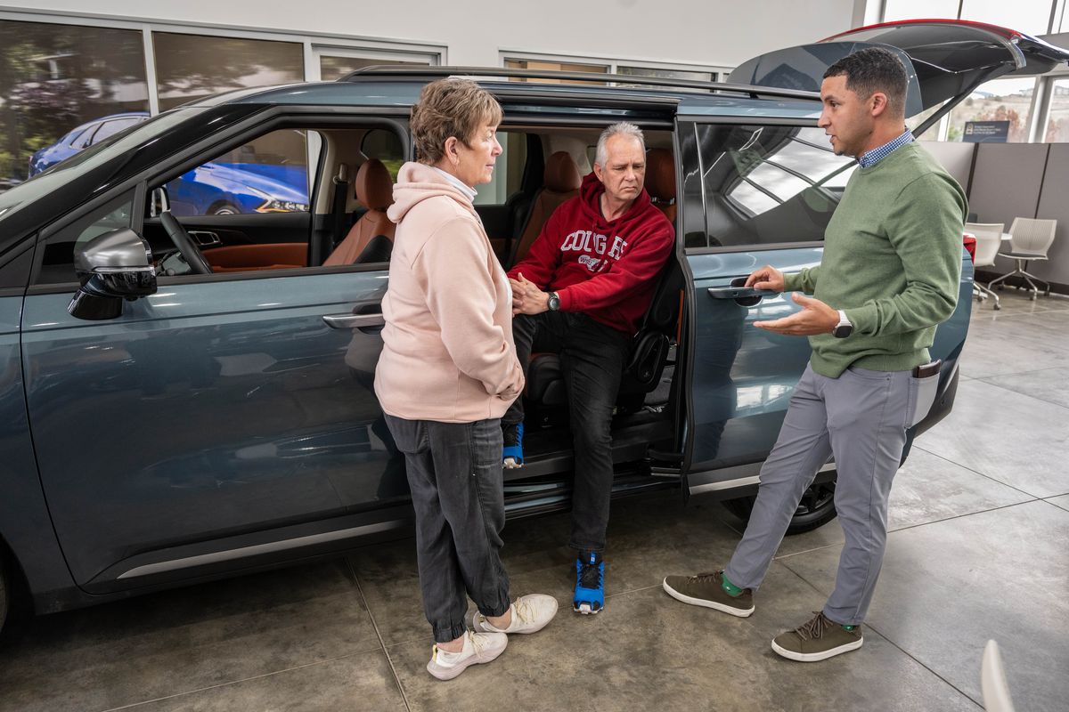 New car salesman Jeff Johnson, on right, speaks with customers Margaret and Brett Hansen at the busy George Gee Kia dealership, Tuesday, April 8, 2025, in Liberty Lake. Local dealerships have seen an increase in motivated customers coming in before the Trump tariffs take effect. (COLIN MULVANY/THE SPOKESMAN-REVIEW)
