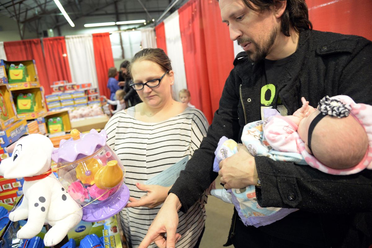 Monique and Thomas Geiger, holding their seven-week-old baby Winnie, pick out toys for Winnie and her older brothers in the toy room at the Christmas Bureau Thursday, Dec. 10, 2015 at the Spokane Fair and Expo Center. Thursday was the first day of the annual charity. JESSE TINSLEY jesset@spokesman.com (Jesse Tinsley / The Spokesman-Review)