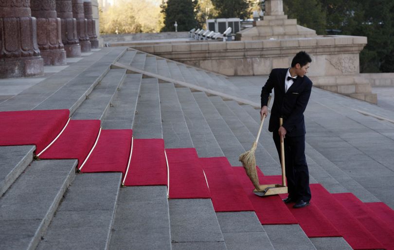 A Chinese staff looks back as he sweeps a red carpet laid out for U.S. President Barack Obama's arrival at the Great Hall of the People in Beijing, China, Tuesday, Nov. 17, 2009. (Ng Guan / Associated Press)