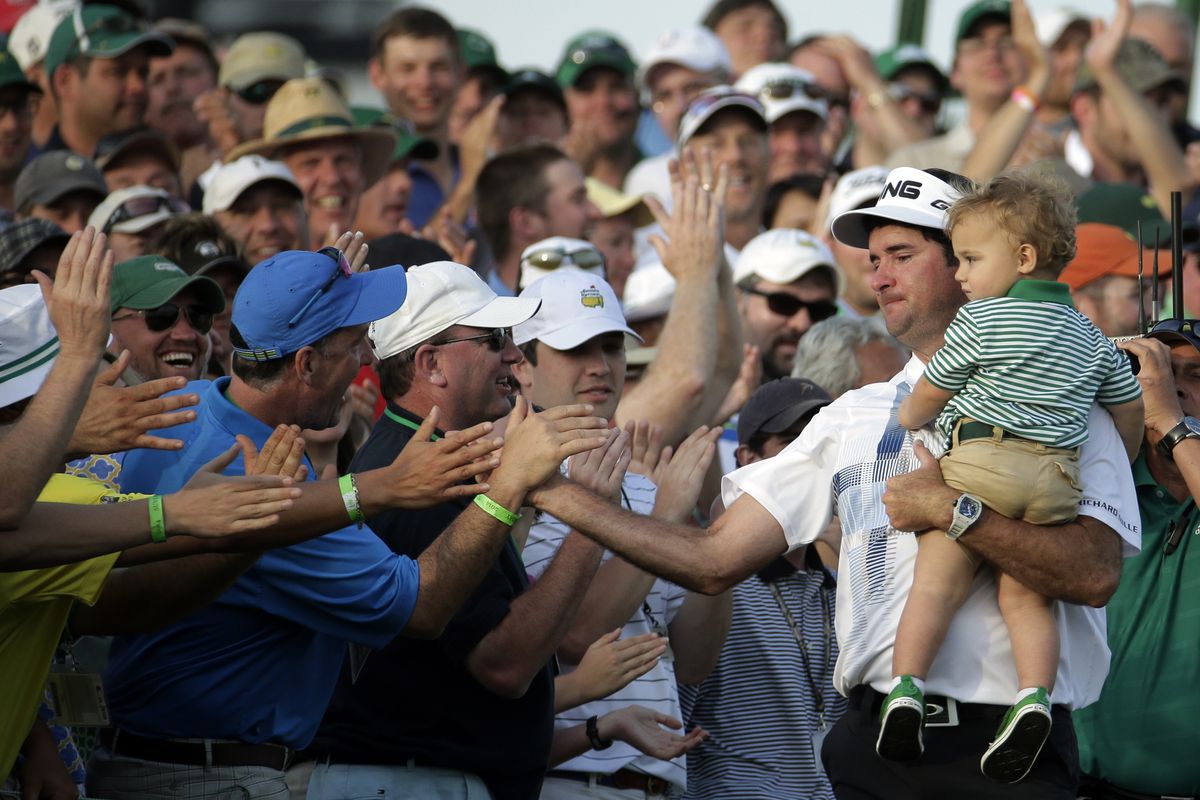 Bubba Watson, carrying son Caleb, shakes hands with fans after winning the Masters. (Associated Press)