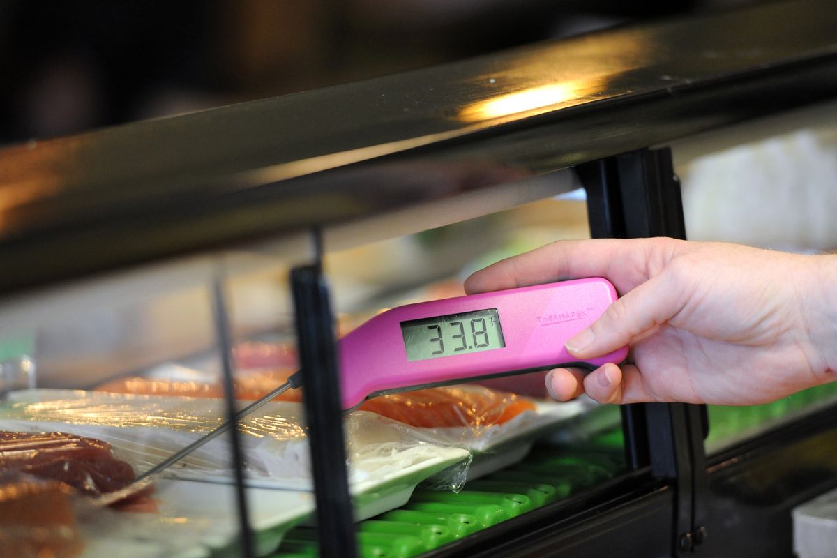 Vikki Barthels pokes a thermometer into fresh fish to check the temperature in the cold case at Sushi I on the South Hill.