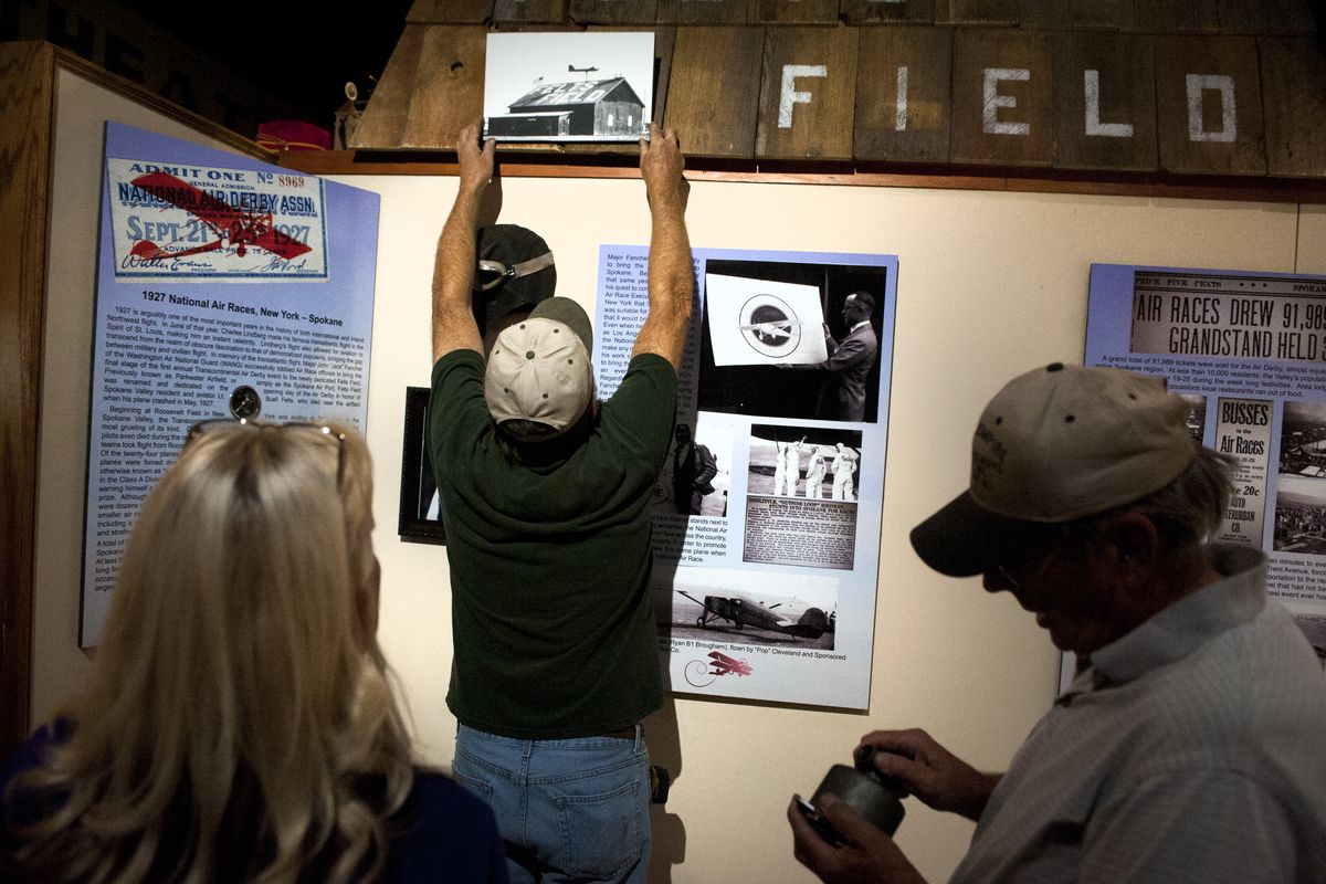 Herman Meier, center, a Spokane Valley Heritage Museum volunteer, raises a photograph of historic Felts Field, as museum director Jayne Singleton, left, looks on Tuesday and volunteer Larry Lenz, right, holds a historic aircraft tachometer for the exhibit in Spokane Valley. (Tyler Tjomsland)