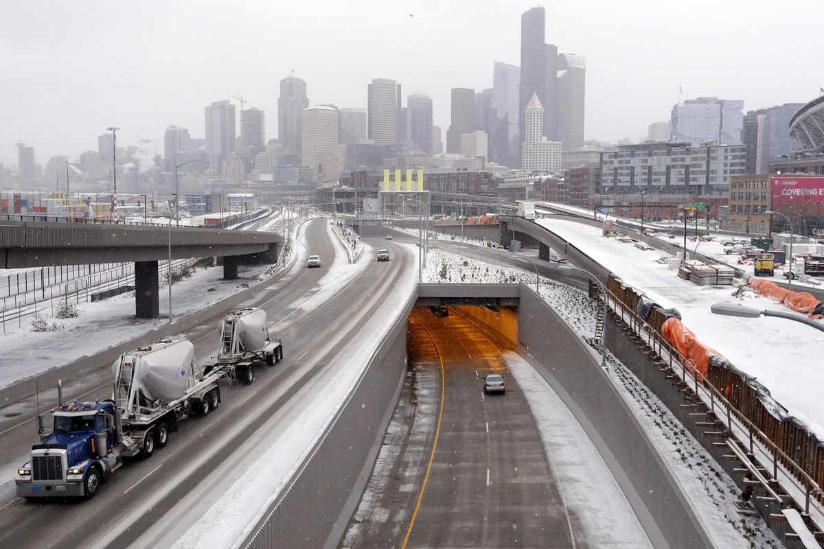 Traffic heads out of the brand new State Route 99 tunnel, left, and in, center, on its first day of service during a winter storm Monday morning, Feb. 4, 2019, in Seattle. Western Washington was hit with several inches of snow, cold temperatures and bone-chilling winds overnight and into the day Monday. (Elaine Thompson / Associated Press)