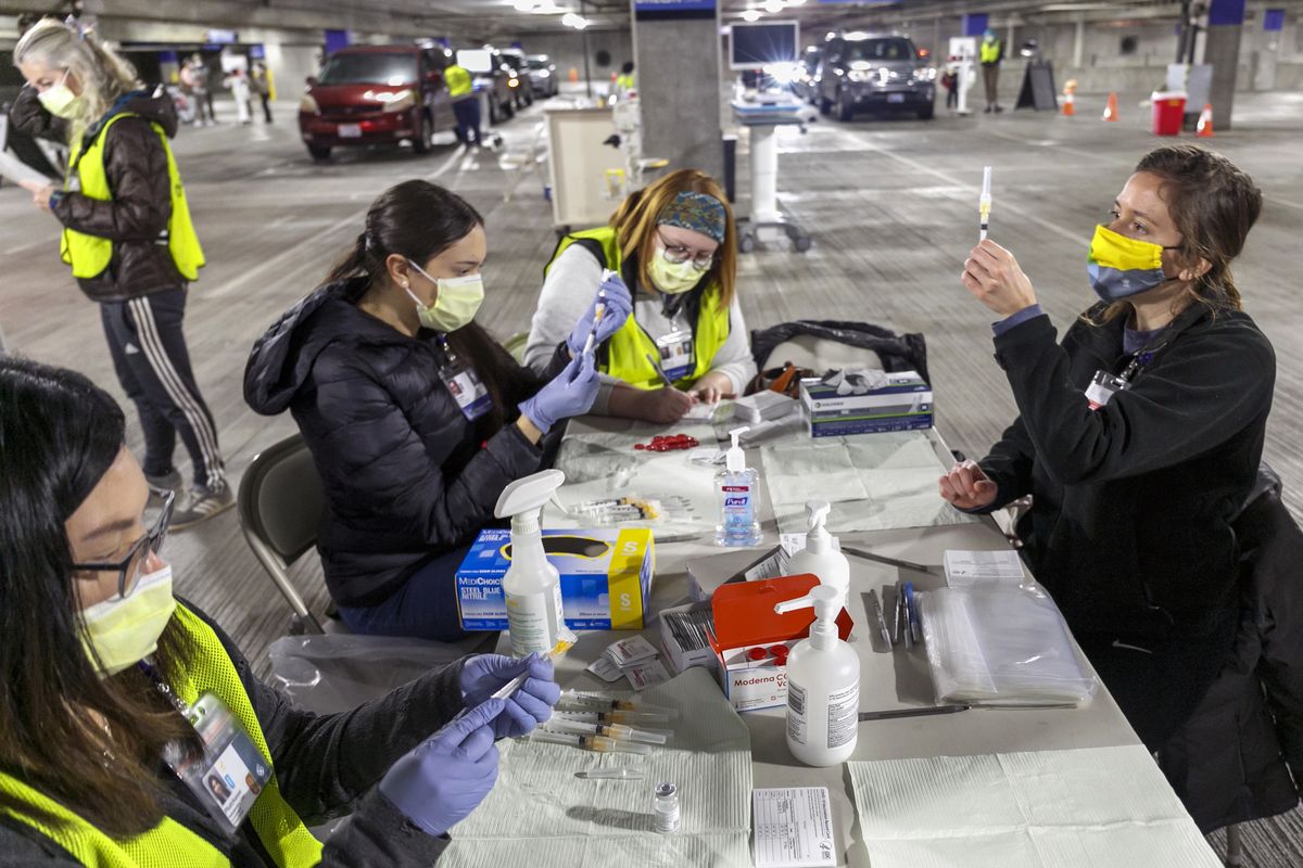In this Jan. 10, 2021 photo, medical professionals from Oregon Health & Science University load syringes with the Moderna COVID-19 vaccine at a drive-thru vaccination clinic in Portland, Ore. Oregon health officials and vaccine advisory committee have made critical, and often controversial, decisions about which groups of people should be prioritized next for the COVID-19 vaccine amid limited supply. Under a new pilot program this week, at least seven federally qualified health centers in Oregon are now able to inoculate whoever they want, even if that patient does not fall into currently eligible categories. (Kristyna Wentz-Graff)