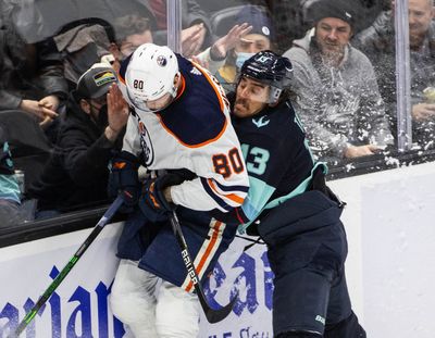 The Seattle Kraken’s Brandon Tanev, right, puts the Edmonton Oilers’ Markus Niemelainen into the boards in the second period at Climate Pledge Arena on Friday, Dec. 3, 2021, in Seattle.  (Tribune News Service)