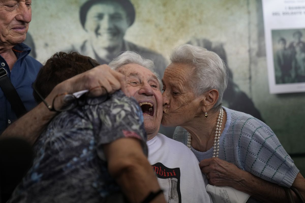 A 97-year-old retired American soldier Martin Adler, center, receives a kiss at Bologna’s airport in Italy on Monday from Mafalda Naldi, right, and Giuliana Naldi, who he saved during World War II. The veteran met three siblings in person for the first time on Monday, eight months after a video reunion.  (Antonio Calanni)