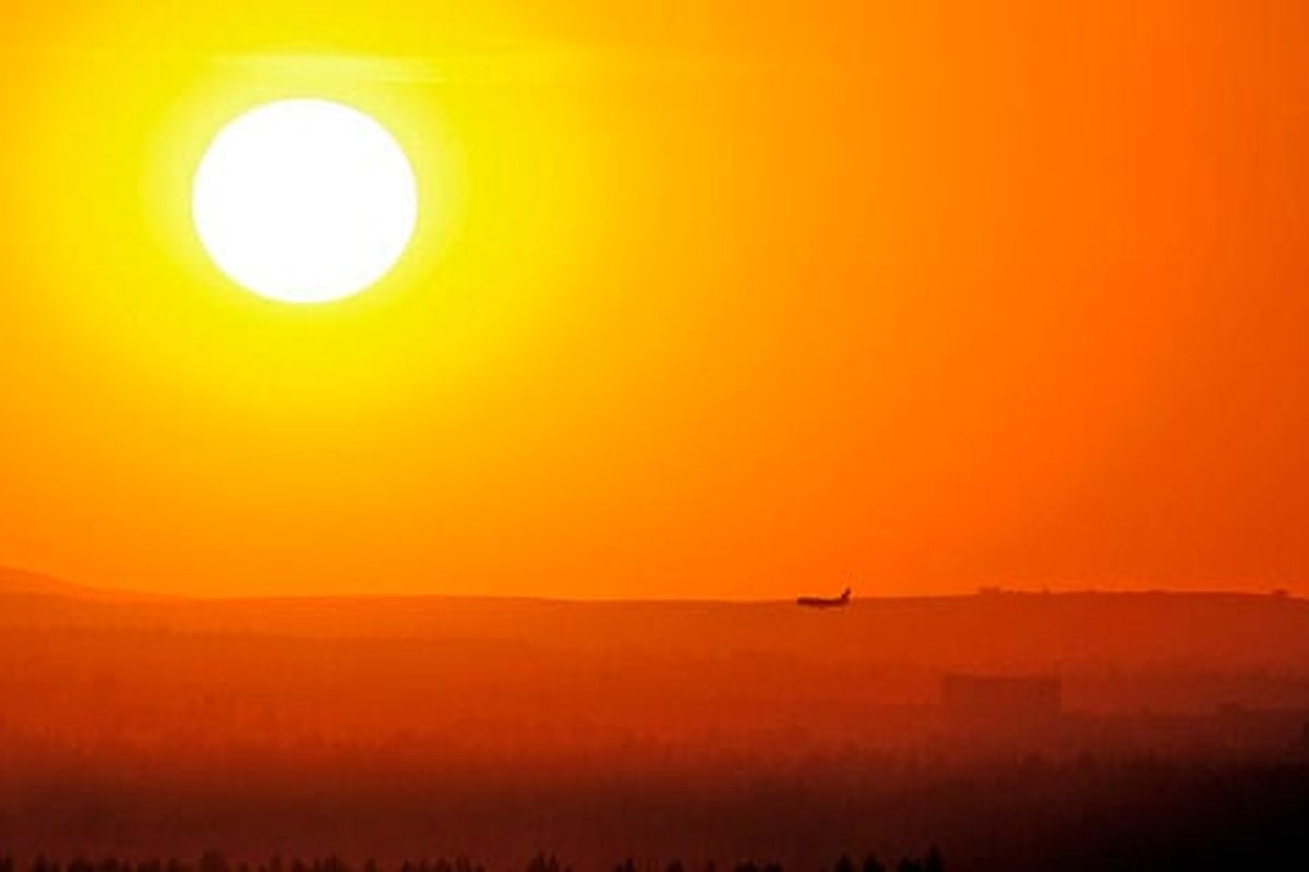 The setting sun turns the smoky haze a burnt orange as a passenger jet prepares to land at Spokane International Airport in this file photo.  (Christopher Anderson)