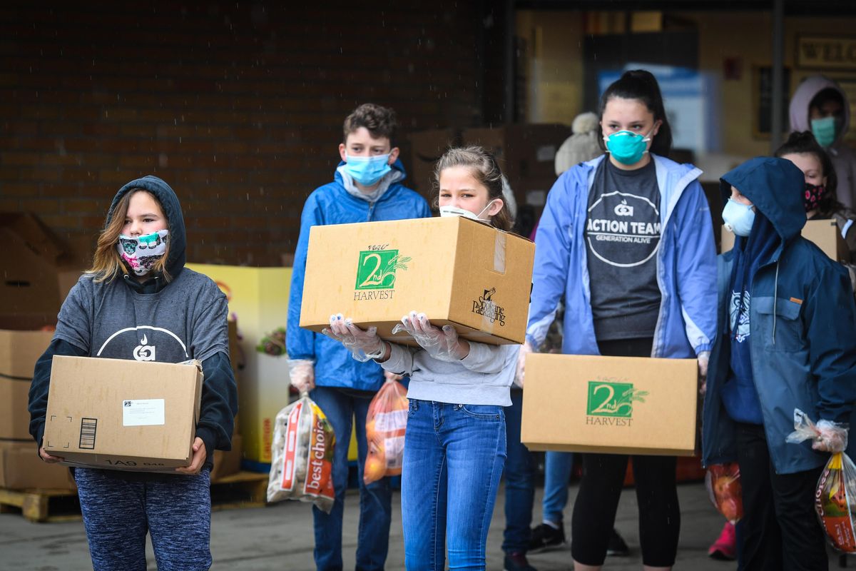 Generation Alive Action Team members wait to distribute fresh produce and frozen meals to families driving to Brentwood Elementary School, Wednesday, May 20, 2020, in Mead, Wash. (Dan Pelle / The Spokesman-Review)