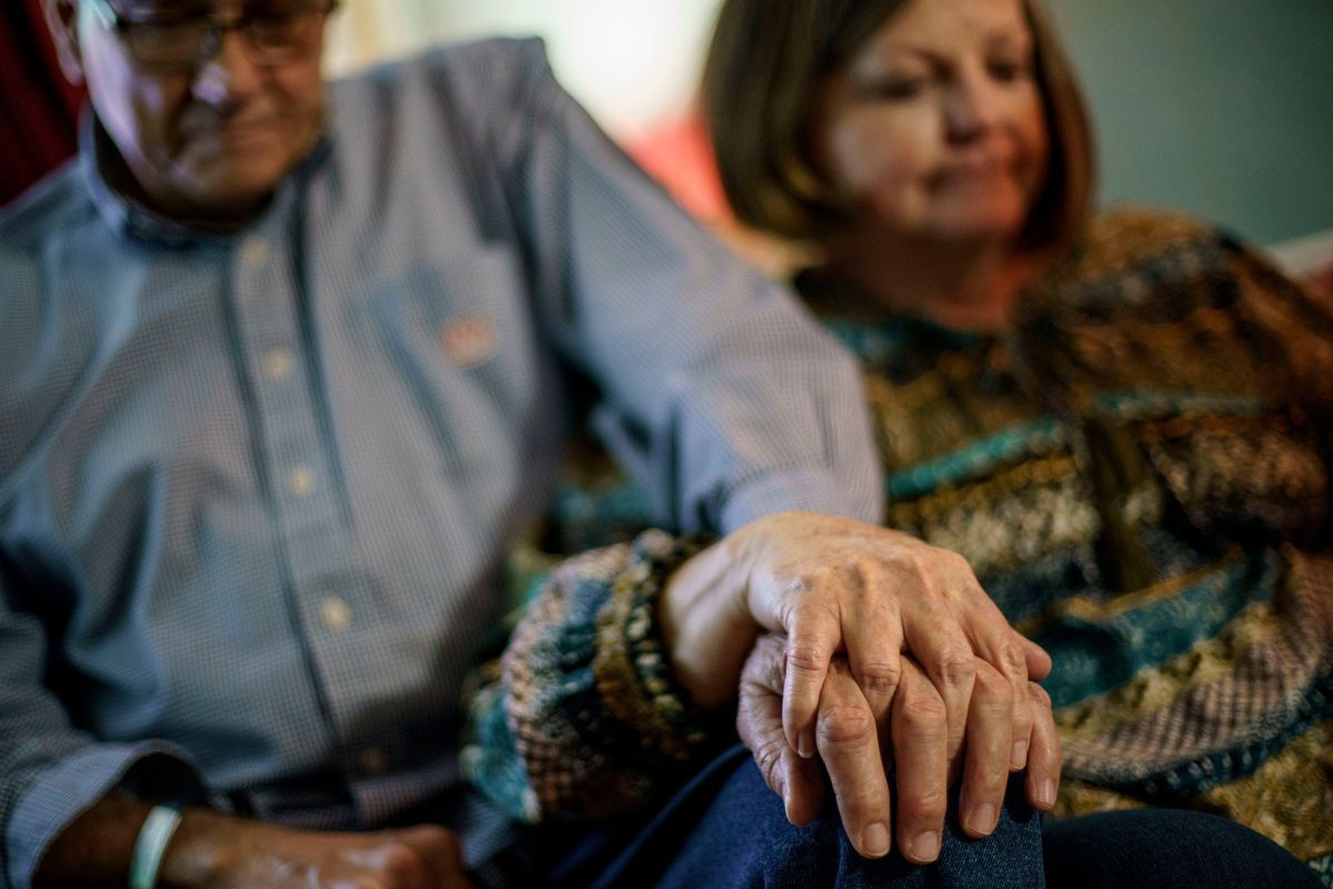 Maryln Curtis, right, aunt of Jennifer McClung, holds hands with her husband, Jim Curtis, at Jennifer's mother's home in Muscle Shoals, Ala., Monday, March 7, 2022. At Helen Keller Hospital staffers knew McClung, a longtime dialysis nurse, as "Mama Jen." When new nurses started, she took them under her wing. Some nights, she woke up crying with worry about her patients, her family says. On Dec. 14, 2020, her lungs severely damaged by the virus, McClung died of COVID-19, just hours before the nation's vaccination campaign began.  (David Goldman)