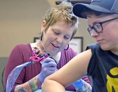 Mount Vernon tattoo artist Darius Sessions creates a tattoo Friday, Dec. 30, 2016, on Rachel Olson at Session’s business, Good Vibes Body Art in Mount Vernon, Wash. (Scott Terrell / Skagit Valley Herald)