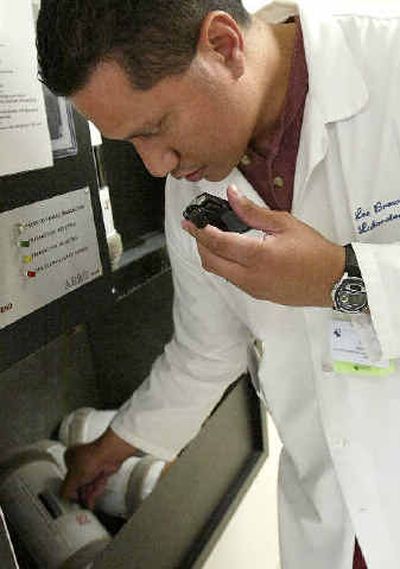 
Labratory tech support specialist Lee Brown talks into his Vocera Wi-Fi communication device as he speaks with another hospital worker in the emergency room area at El Camino Hospital in Mountain View, Calif.
 (Associated Press / The Spokesman-Review)