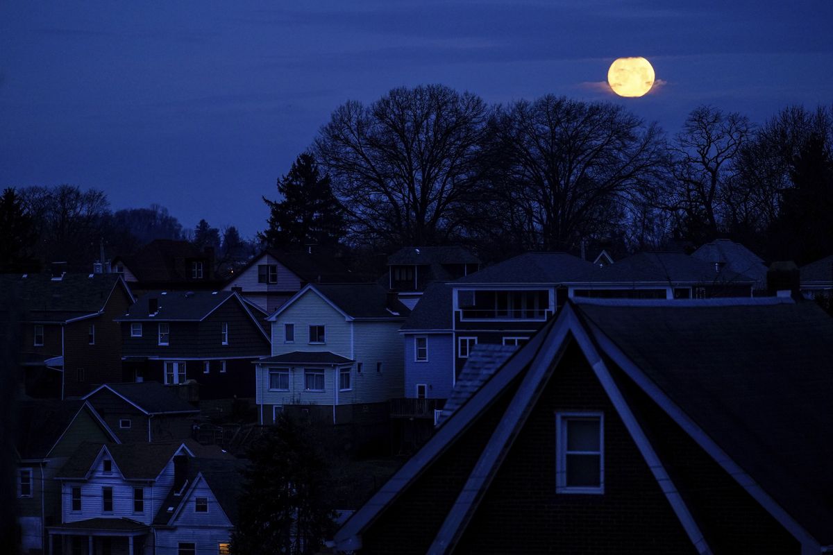 The moon sets behind homes in Pittsburgh, Thursday, March 17, 2022. Around the country, as child welfare agencies use or consider algorithmic tools like in Allegheny County, an Associated Press review has identified a number of concerns about the technology, including questions about its reliability and its potential to harden racial disparities in the child welfare system.  (Matt Rourke)