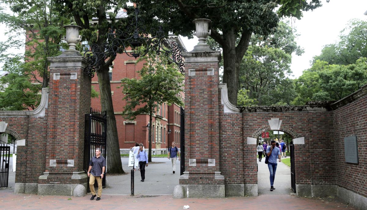 FILE - In this Aug. 13, 2019, file photo, pedestrians walk through the gates of Harvard Yard at Harvard University in Cambridge, Mass. Harvard and the Massachusetts Institute of Technology filed a federal lawsuit Wednesday, July 8, 2020, challenging the Trump administration