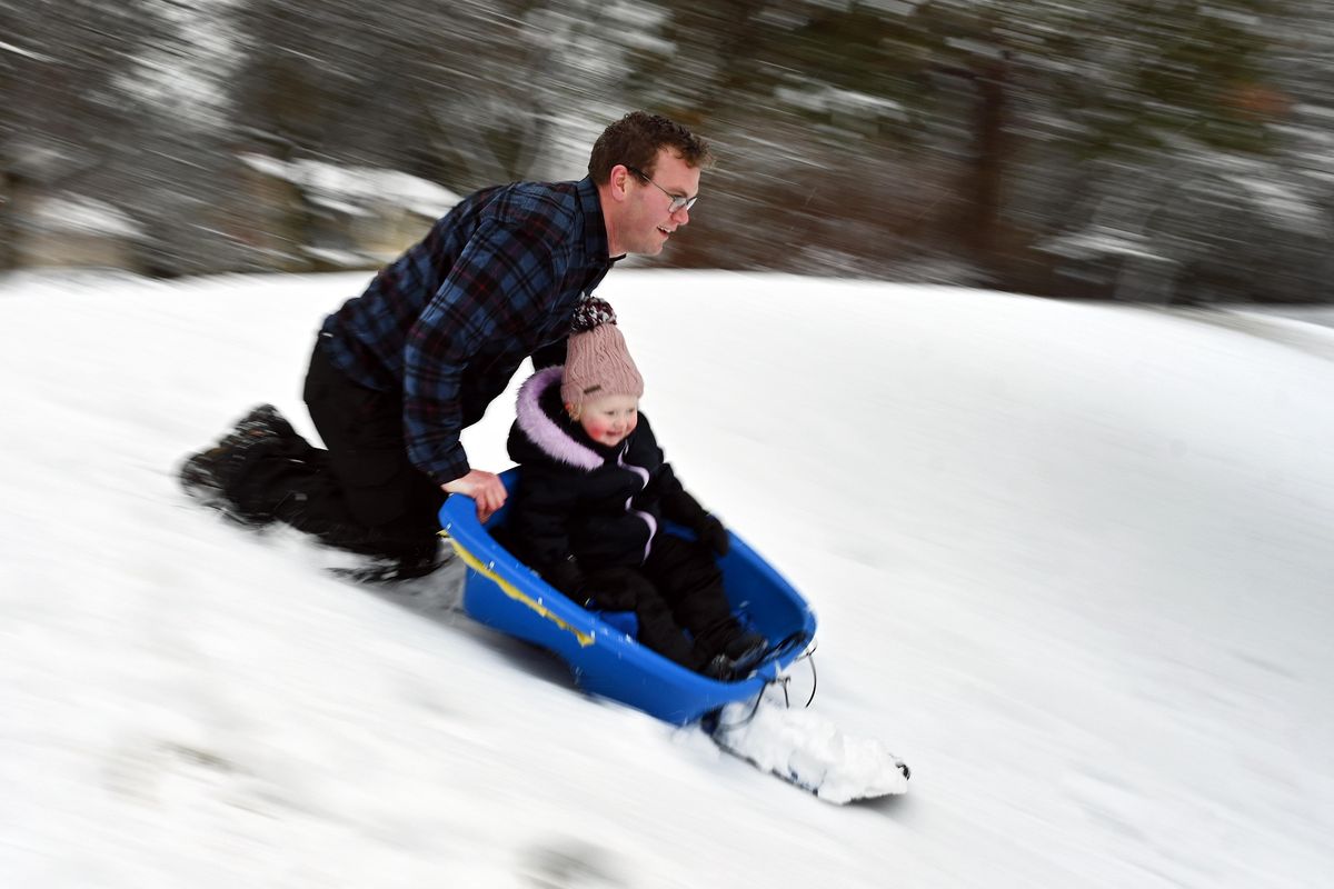 Ben Gilsdorf joins his daughter Cora 2, on the sledding hill at Cannon Hill Park, Tuesday, Dec. 31, 2019. (Colin Mulvany / The Spokesman-Review)