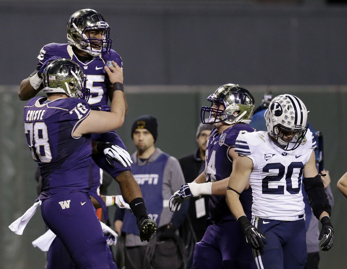 Washington running back Bishop Sankey is lifted by teammate Mike Criste after Sankey scored one of his two TDs Friday night. (Associated Press)