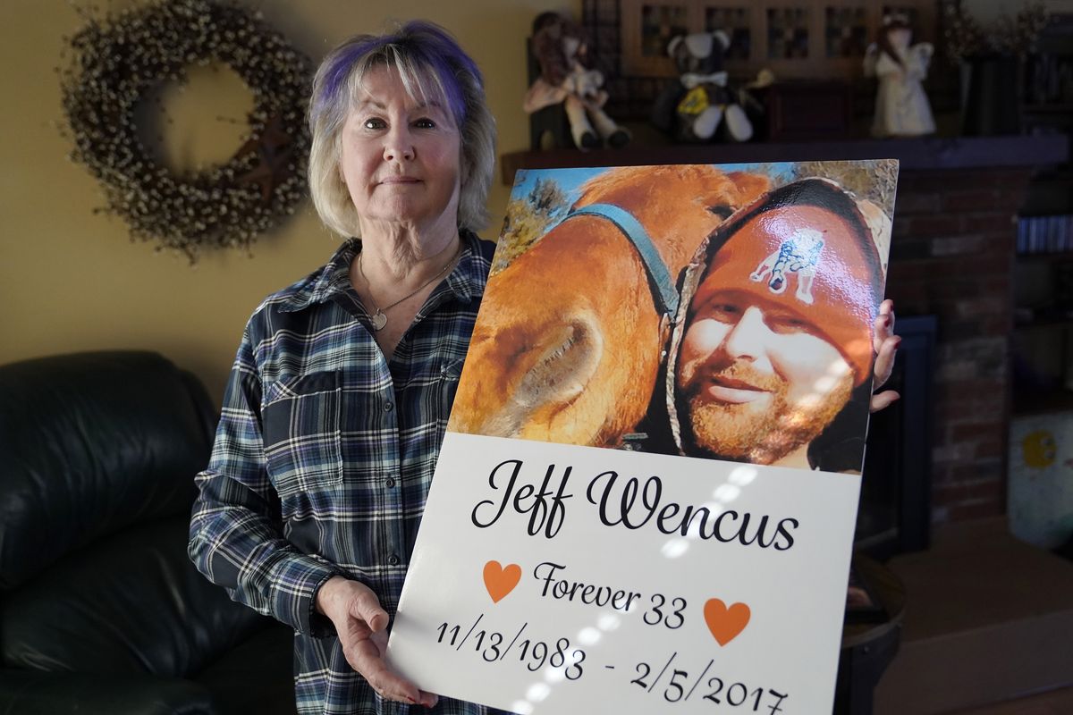 Lynn Wencus, of Wrentham, Mass., holds a poster, with a likeness of her son Jeff, at her home, in Wrentham, Wednesday, March 2, 2022. Wencus lost her son to a heroin overdose in 2017. OxyContin maker Purdue Pharma and virtually all U.S. states have agreed to a new settlement of opioid lawsuits. The deal reached Thursday, March 3, 2022, would require members of the Sackler family who own the drugmaker to pay $5.5 billion to $6 billion in cash. They also apologized. A bankruptcy judge must still approve the deal.  (Steven Senne)