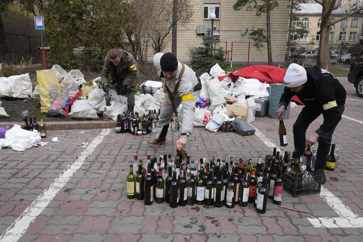 Members of civil defense prepare Molotov cocktails in a yard in Kyiv, Ukraine, Sunday, Feb. 27, 2022. A Ukrainian official says street fighting has broken out in Ukraine