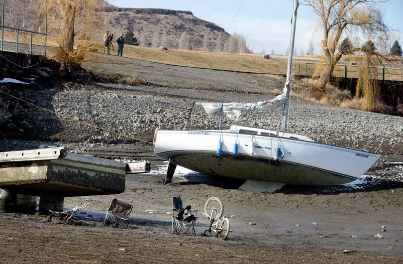 A sailboat owned by Bryan Stockdale, of Vantage, Wash., is left in the mud at the Vantage Riverstone Resort dock in Vantage on Monday, March 3, 2014, as up to 20 feet of water is let out of the Columbia River reservoir behind Wanapum Dam after a spillway pillar was discovered to be cracked at the dam last week. Garbage is seen that had been left in the water at the end of the dock. (Associated Press)