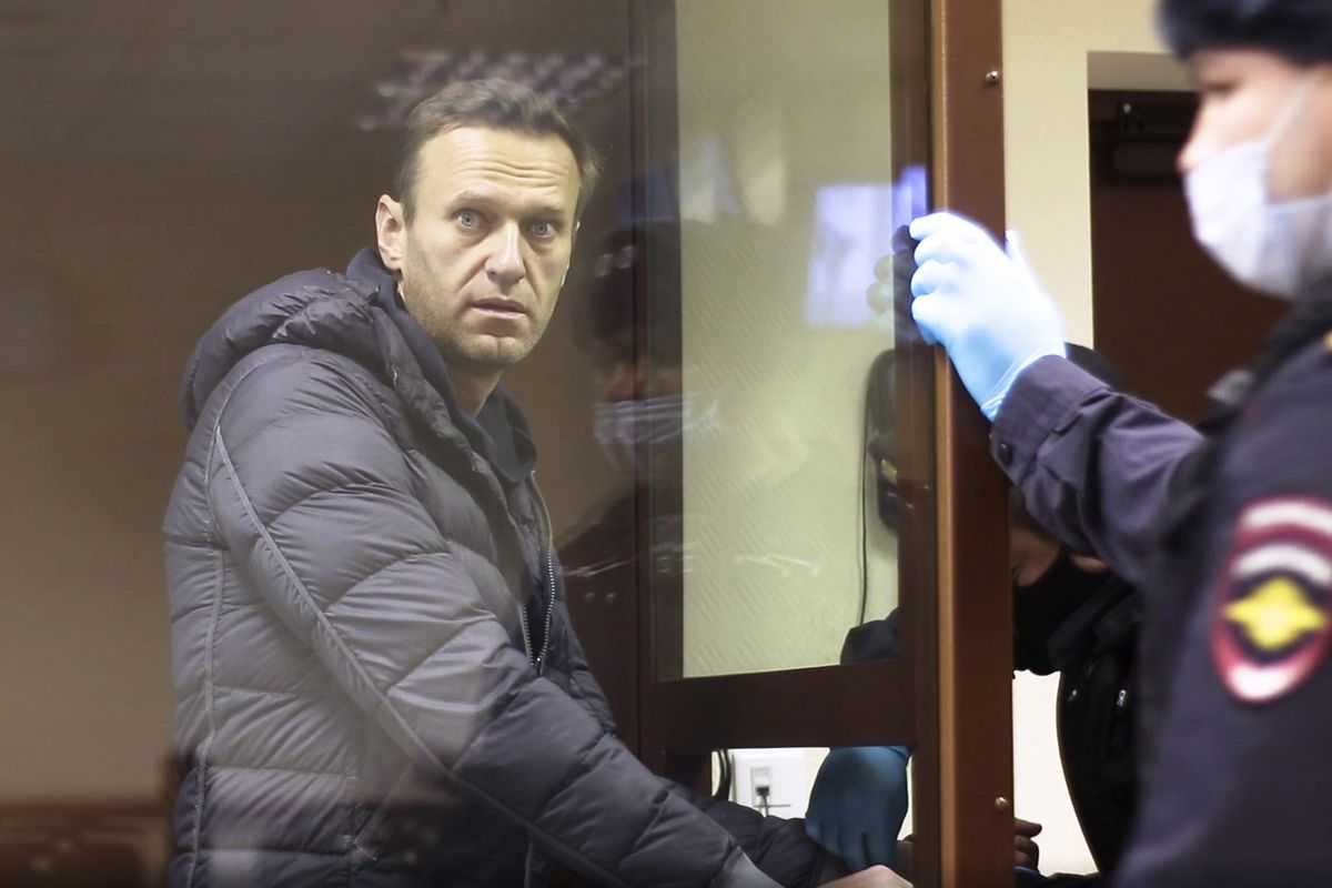 In this image made from video provided by the Babuskinsky District Court, Russian opposition leader Alexei Navalny stands in a cage during a hearing on his charges for defamation, in the Babuskinsky District Court in Moscow, Russia, Friday, Feb. 5, 2021. Navalny was accused of slandering a World War II veteran featured in the video promoting the constitutional reform allowing to extend President Vladimir Putin