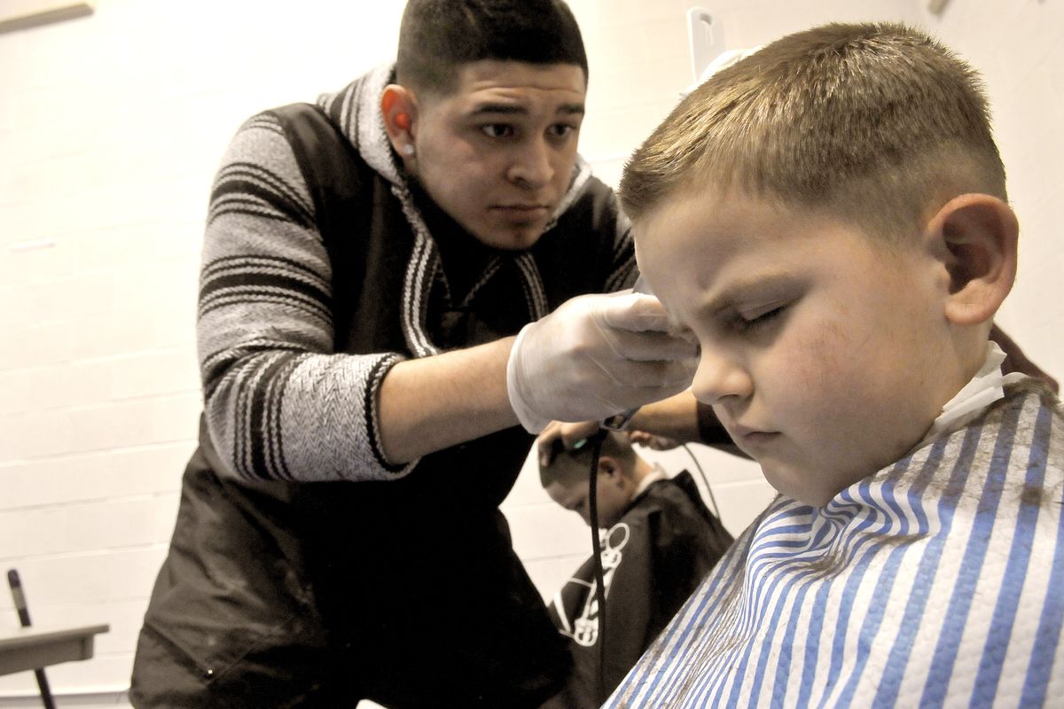 Shawn Martinson, 6, closes his eyes as barber intern David Moreno of Quick’s Barbershop gives him a haircut at Homeless Connect, a day of services at Emmanuel Life Center on Thursday. (Jesse Tinsley)