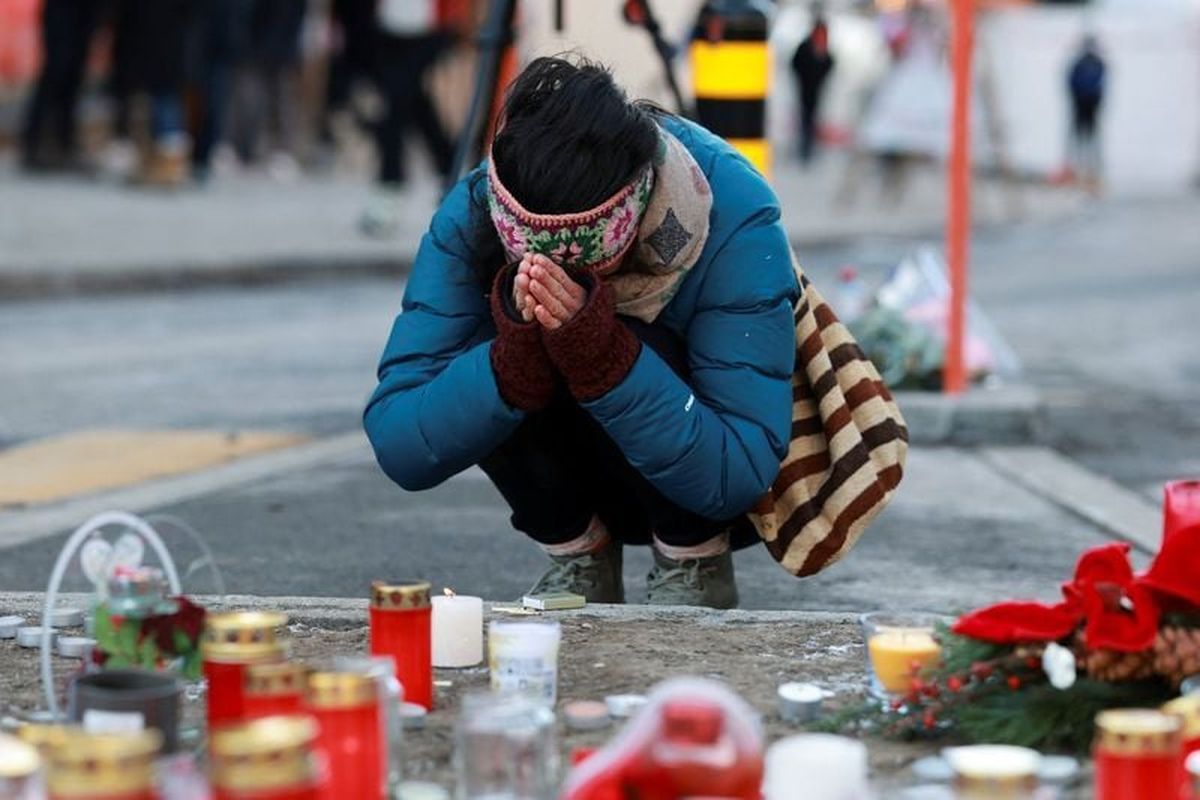 A person pays tribute next to the candles placed for the victims outside the "Le Constellation" bar, after a fire and explosion during a New Year