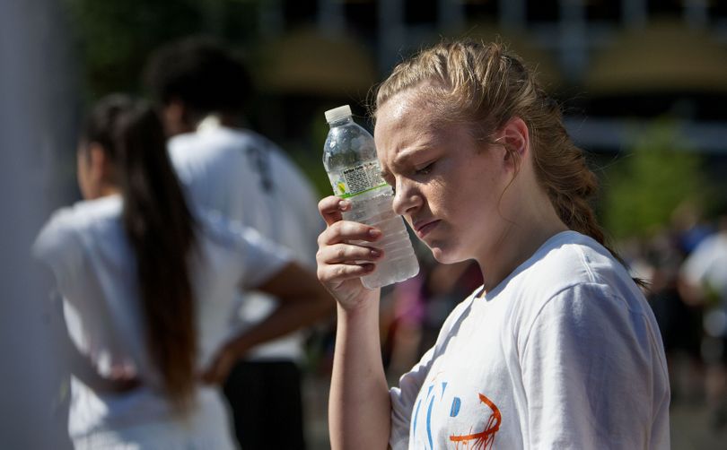 Thirteen-year-old Riley Hall of Spokane uses her water bottle to battle the heat during Hoopfest on Saturday, June 27, 2015. (Kathy Plonka)