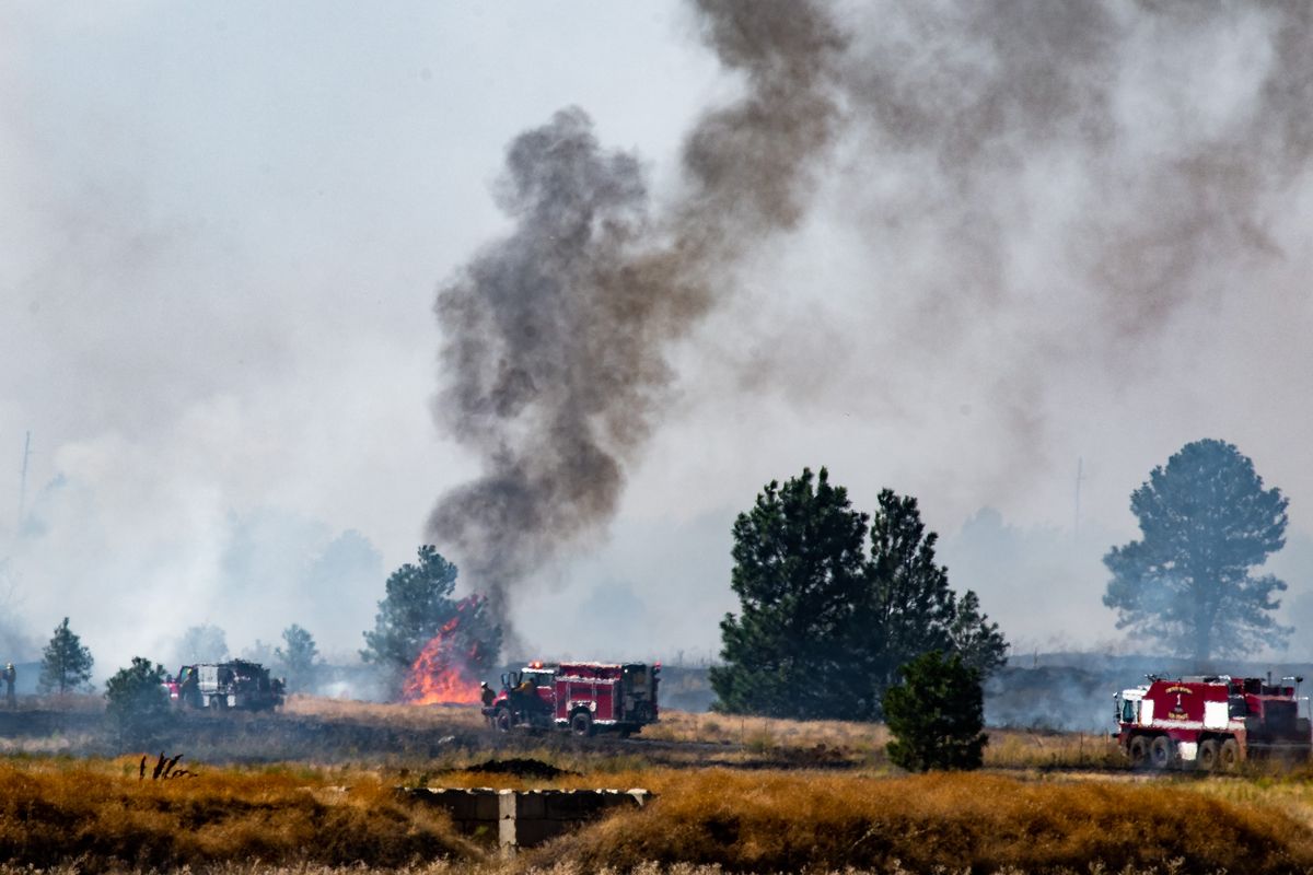 Firefighters work to contain a brush and timber fire Thursday that burned its way onto Fairchild Air Force Base.  (Colin Mulvany/THE SPOKESMAN-REVIEW)