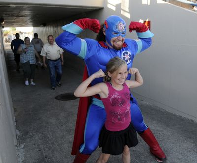 Popular Spokane Indians superhero Recycle Man poses for pictures with a young recycler before a recent ballgame. “You, too, can be a hero if you recycle,” he says. (J. Bart Rayniak)