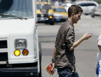 Giancarlo Yerkes, a 30-year-old advertising employee, crosses a street in downtown Chicago while text-messaging with his cell phone. In an alert issued this week, the American College of Emergency Physicians says based on reports from emergency-room doctors around the country, the number of text-messaging pedestrians, bicyclists, rollerbladers and even motorists who injure themselves is rising. Yerkes admitted he once walked straight into a stop sign while texting and bumped his head.  (Associated Press / The Spokesman-Review)