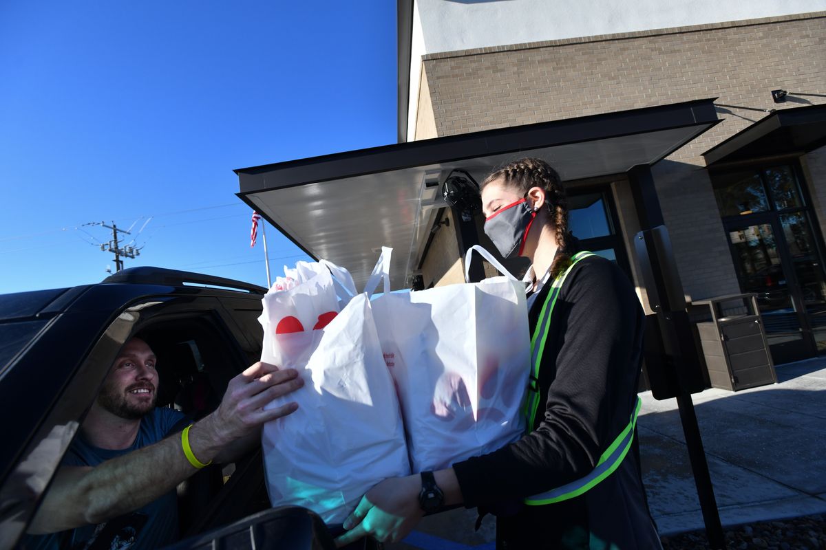 Ryan Heacock, owner of Fellowship Financial Planning smiles as he takes an order of A Chick-fil-A for his staff from an employee who could not be identified due to company regulations after he waited several hours in line on Dec. 1, 2020, at 9304 N. Newport Highway in Spokane. Heacock said the wait was worth it and that he got a lot of paperwork done in the car.  (Tyler Tjomsland/THE SPOKESMAN-RE)