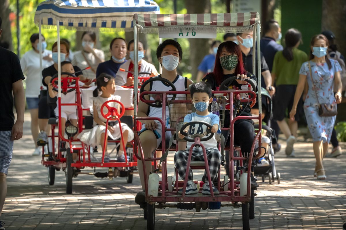Adults and children ride pedal cycles Saturday at a public park in Beijing.  (Mark Schiefelbein)