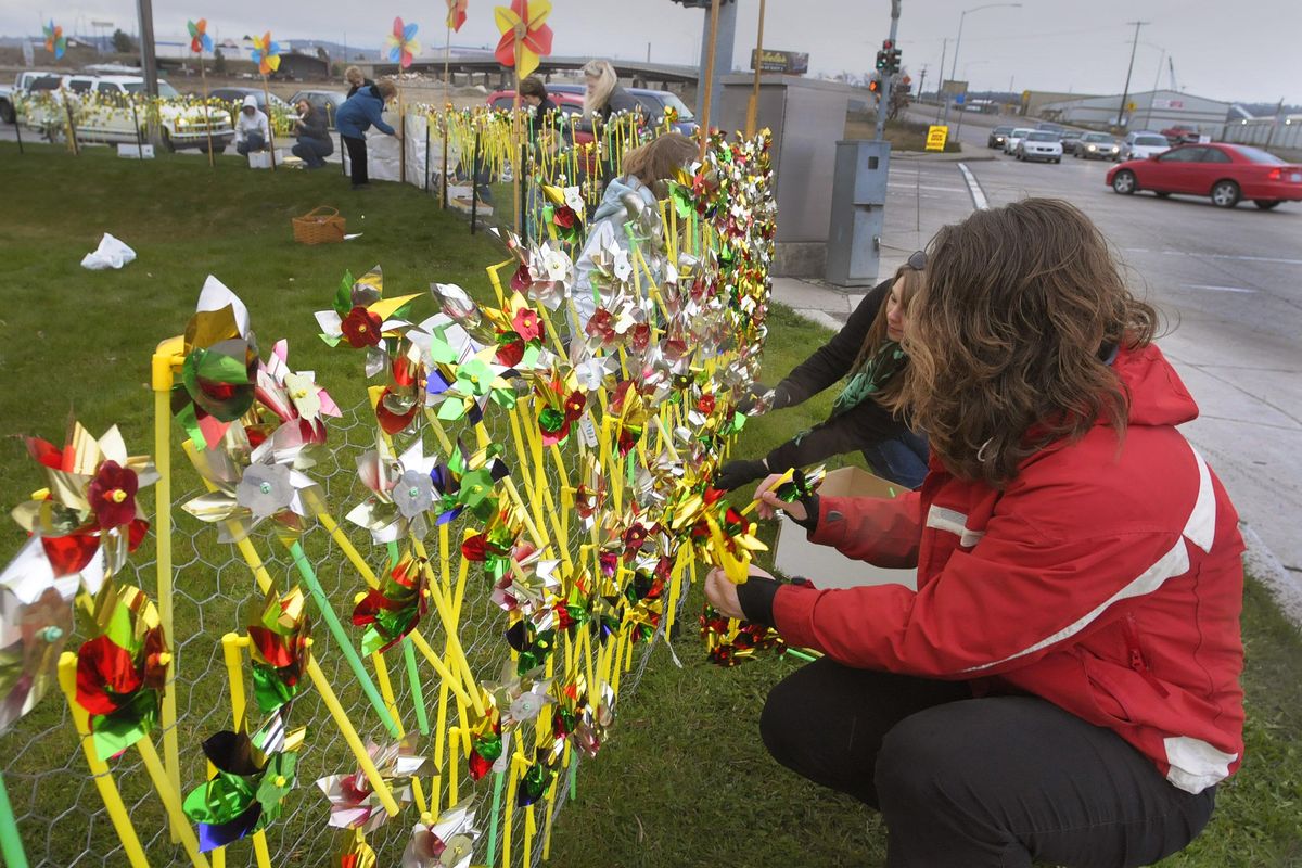 FILE - Dena Chappell, front in red, and other Head Start program staff decorate the corner of Mission and Greene with pinwheels in the wind and rain in this 2010 photo. (Christopher Anderson / The Spokesman-Review)