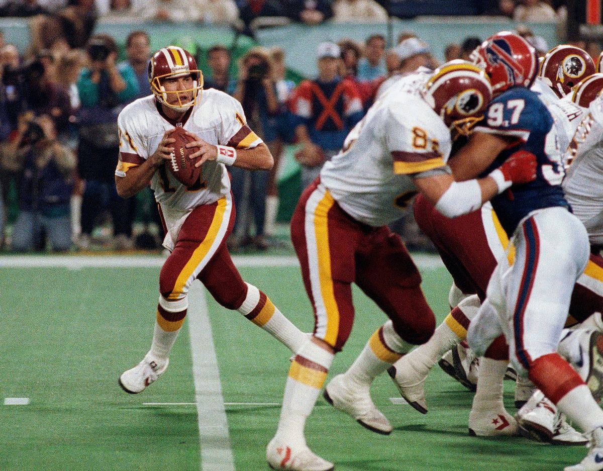 Mark Rypien, pictured at left during Super Bowl XXVI in 1992, has been sued by his longtime domestic partner alleging physical and emotional abuse over a period of 12 years. Rypien has admitted to violence in the past, and says he believes he suffers from chronic traumatic encephalopathy caused by repeated head trauma while playing football.  (Associated Press)