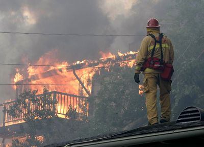 A Salinas Fire Department firefighter stands watch over a home as it burns in Santa Barbara, Calif., on Wednesday.  (Associated Press / The Spokesman-Review)