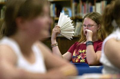 
Centennial Middle School sixth-grader Shala Elliott cools herself with a paper fan Wednesday in the library of the Spokane Valley school. 
 (Liz Kishimoto / The Spokesman-Review)