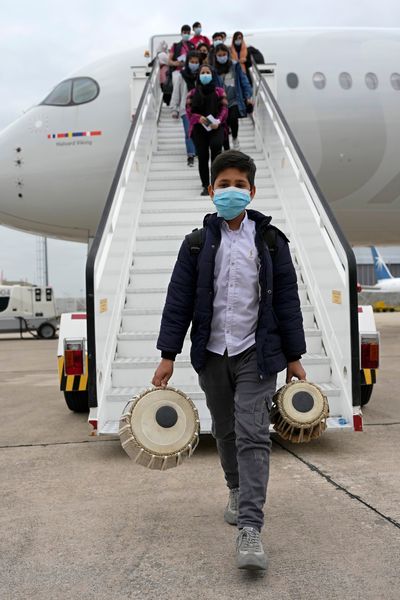 An Afghan boy carrying musical instruments disembarks from an airplane at Lisbon military airport on Monday. He is among a group of 273 students, faculty members and their families from the Afghanistan National Institute of Music who are getting a new start in Portugal.  (Associated Press)