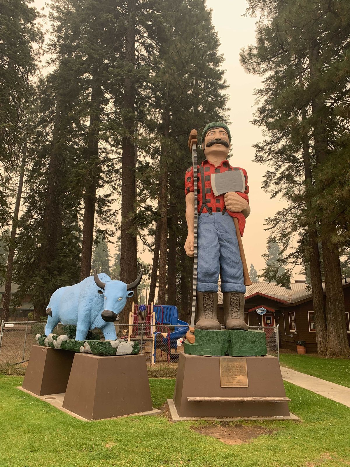 Statues of Paul Bunyan, and his Big Blue Ox are seen in Westwood, Calif., Friday, Aug. 13, 2021. The statues carved from a nearly 1000 year old tree Redwood log 22 feet long and 12 feet in diameter, and weighing 28,000 pounds, are threatened by the fires. In California, the Dixie Fire that virtually destroyed the Sierra Nevada town of Greenville is less than a third surrounded. Fire officials say Northern California will have dangerous fire weather on Friday, including possible lightning that could spark more blazes.  (Eugene Garcia)