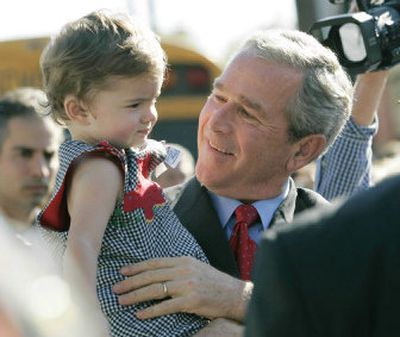 
President Bush carries an unidentified toddler on a campaign stop Monday in Statesboro, Ga. 
 (The Spokesman-Review)