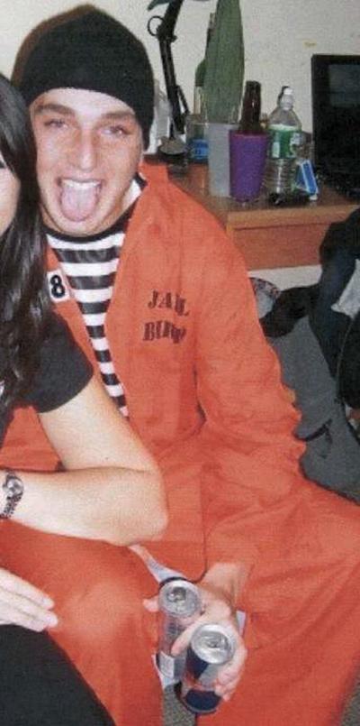 This photo shows Joshua Lipton, posing at a Halloween party while wearing a prisoner costume of a striped shirt and orange jumpsuit labeled 