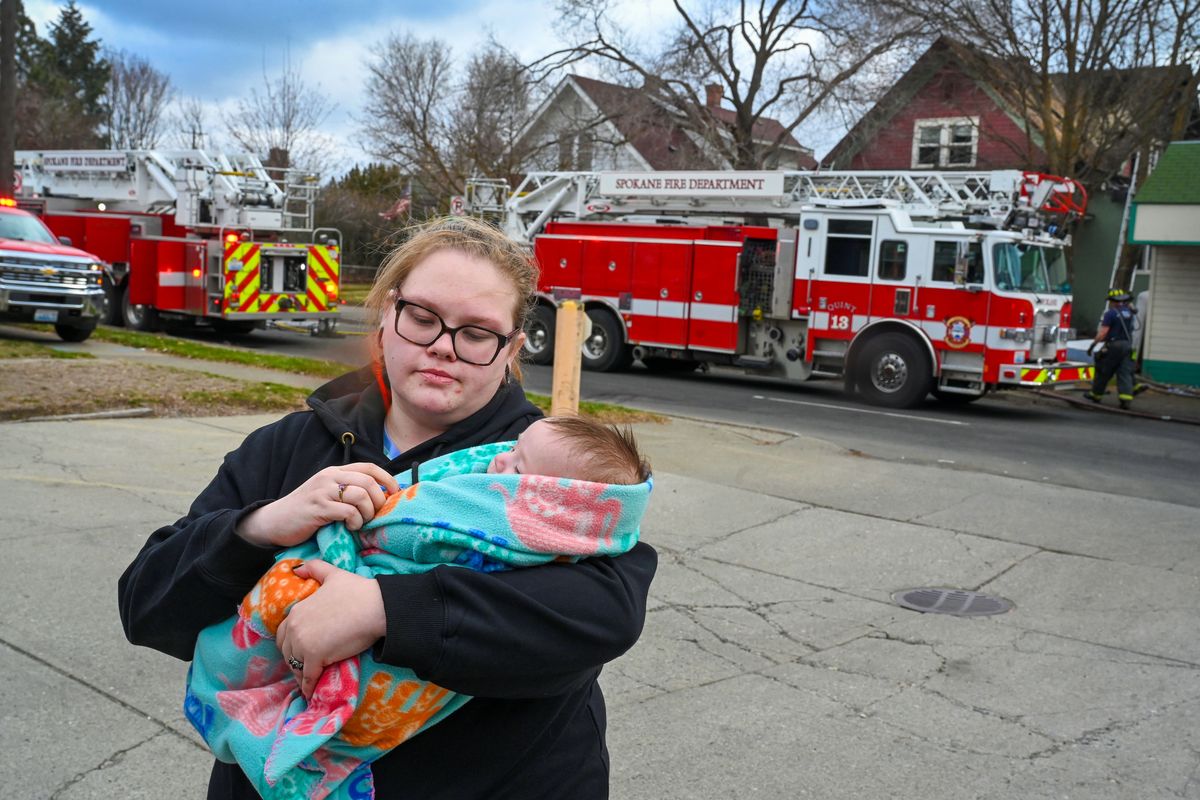 Heather Hall comforts her son, Owen McFarlane, 3 months, after a fire broke out in the house she resided in, far right, Thursday in Spokane’s Garland Business District.  (DAN PELLE/THE SPOKESMAN-REVIEW)