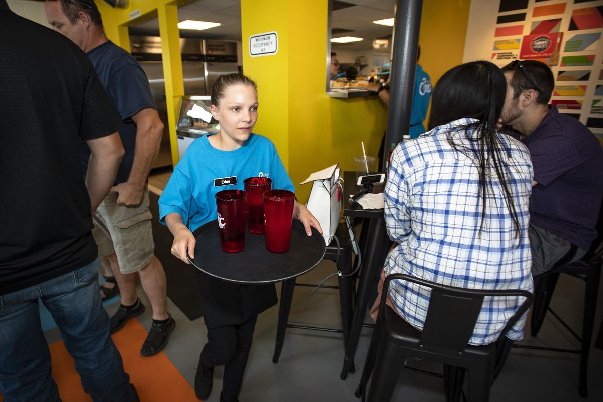 During the grand opening of Fresh Soul, a new soul food restaurant in Spokane’s East Central neighborhood, Edee Morse, 14, brings water to patrons Thursday, July 19, 2018. Morse is one of the teens ages 14 to 18 that earn minimum wage at Fresh Soul as they take part in a 16-week-long internship and tutor program. (Colin Mulvany / The Spokesman-Review)