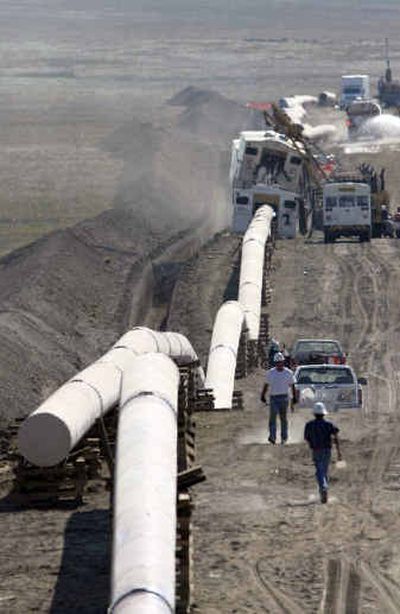 
Workers walk past sections of welded 36-inch natural gas pipeline nearing completion near the Pawnee National Grasslands northeast of Fort Collins, Colo., in August. 
 (File/Associated Press / The Spokesman-Review)